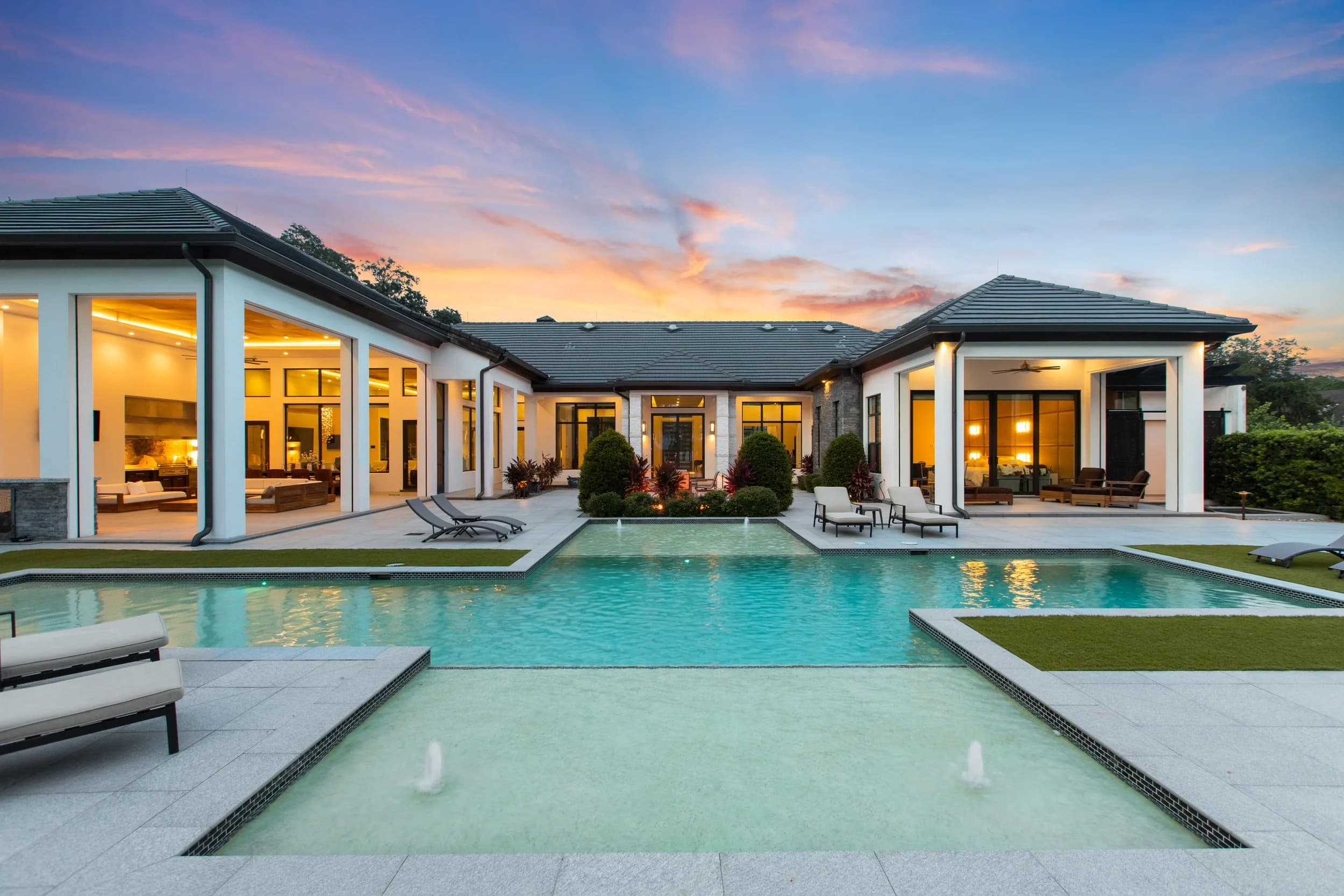 Rear elevation of a luxury Florida home at twilight, interiors glowing over the pool